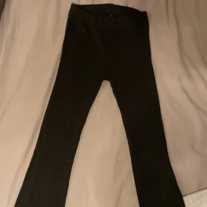 Svarta ribbade byxor - Snygga svarta ribbade byxor med en tight passform. Perfekta för en stilren look och kan enkelt matchas med olika toppar. Byxorna har en elastisk midja för extra komfort.