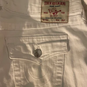 Fina vita jeans från True Religion - Snygga vita jeans från True Religion med bootcut-stil. De har en lågmidja och klassiska fick detaljer. Båda knapparna finns därbak hade bara inte knäppt dom.