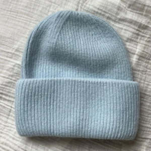 Ljusblå stickad mössa - Snygg och enkel ljusblå stickad mössa med ribbad design. Perfekt för kyliga dagar och ger en stilren look. Passar bra till både vardag och utflykter.