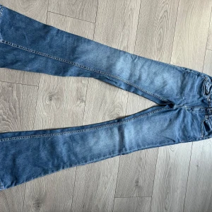 Jeans  - Snygga blå jeans från Reserved i en klassisk denimstil. De har en utsvängd passform och är perfekta för en avslappnad look. Jeansen har fem fickor och knappar i midjan. 34
