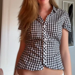 Svartvit rutig blus - Snygg svartvit rutig blus med korta ärmar och knappar framtill. Perfekt för en stilren look.