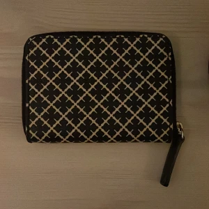Plånbok från Bymalenebirger🖤 - Snygg plånbok med ett rutigt mönster i svart och vit. Den har en praktisk dragkedja och en stilren design som passar perfekt i de flesta väskor.