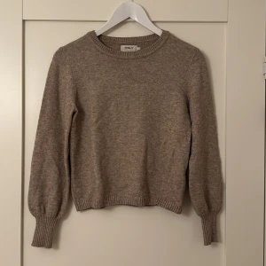 Beige stickad tröja från ONLY - Relativ tunn stickad långärmad tröja med ribbade muddar, använts ett par fåtal gånger. Tröjan är som gott som ny utan några skador. Nypris: 300kr