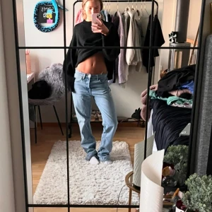 Ljusblå straightleg jeans - Säljer ett par ljusblå raka jeans med lågmidjade med en avslappnad passform. De har en klassisk femficksdesign och knappgylf. Perfekta för en casual look.