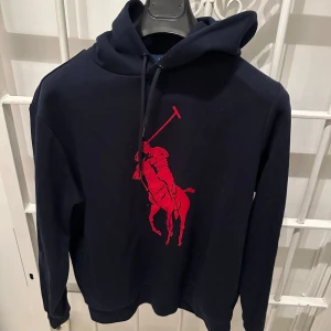 Ralph Lauren hoodie  - Snygg mörkblå hoodie från Polo Ralph Lauren med ett stort tryck på magen. Tröjan är i extremt bra skick, knappt använd. Köpt i USA för typ 1500. Den är i large men skulle säg att den passa M också. 