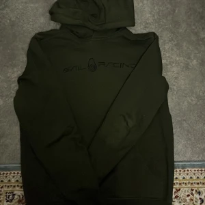 Mörkgrön hoodie från Sail Racing - Säljer en mörkgrön hoodie från Sail Racing med en stilren design. Tröjan har en klassisk huva och är perfekt för kyligare dagar. Den är i storlek S och har en diskret logga på bröstet.