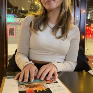 Långärmad croppad topp från Chiquelle - Beige/gräddvit ribbad croppad topp från Chiquelle. Toppen har långa ärmar och en tight passform, perfekt för en stilren look.