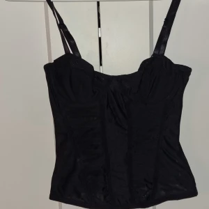 Svart korsett - Snygg svart korsett från h&m med justerbara axelband och hakknäppning där bak. Tillverkad i ett mjukt och bekvämt material som är lite see through. Säljer då den är för liten för mig, hade behålla den annars då den är jättefin🥹