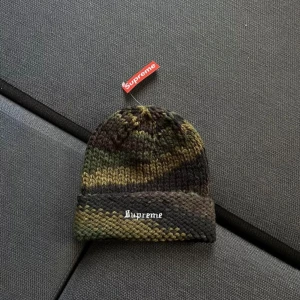 Supreme beanie  - Snygg och trendig mössa från Supreme i ett coolt camouflage-mönster. Perfekt för att hålla dig varm och stilren under kyliga dagar. Mössan har en broderad Supreme-logga framtill.
