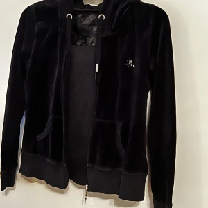 Svart hoodie från Cubus - Snygg svart hoodie från Cubus i mjuk bomullsblandning med dragkedja och huva. Perfekt för en avslappnad stil. Den har långa ärmar och praktiska fickor framtill.