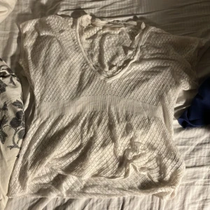 Vit spetsblus från Cream - Säljer en söt vit spetsblus från Cream med v-ringning och korta ärmar. Blusen har ett fint mönster och en ribbad midja som ger en smickrande passform. Perfekt för en somrig look!