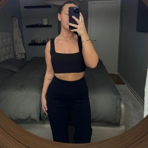 Svart croppad linnetopp från Nly One - Snygg svart croppad linnetopp från Nly One. Toppen har en stilren design med breda axelband och en fyrkantig urringning. Perfekt för en trendig look. Aldrig använd och normal i storleken 