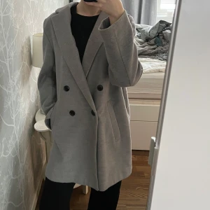 Grå kappa - Snygg grå kappa med dubbelknäppning och klassisk krage. Passar för kort och lång, tjej och kille. Jag är 169cm lång och brukar vanligtvis ha storlek S, så på mig blir kappan lite längre. Passar både till vardags och mer uppklädda tillfällen. Perfekt till kallare sommarkvällar eller en varm vinterdag, eller varför inte till höst eller vår.☺️ I väldigt bra skick!