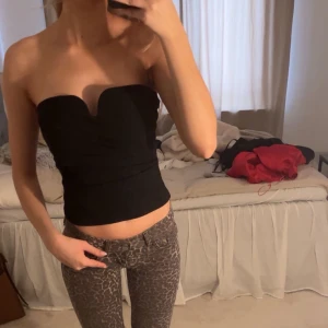 Svart tubtopp - Snygg svart tubtopp med en stilren design. Perfekt för en kväll ute eller en avslappnad dag. Toppen är axelbandslös och har en tight passform som framhäver figuren.