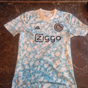 Ajax fotbollströja  -  Ajax fotbollströja från Adidas med ett snyggt blått-vitt mönster. Säljer denna tröja eftersom den passar inte mig längre. Priset är inte fast 