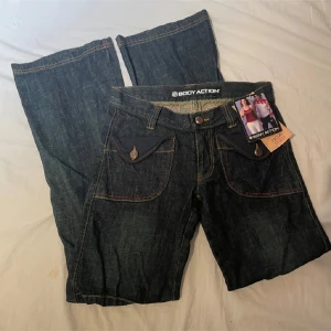 Bootcut jeans  - Snygga mörkblå jeans från Body Action med kontrastsömmar och unika fickdetaljer. Jeansen har en klassisk femficksdesign och knappar framtill. Lappen är inte kvar men dom är knappt använda. Stolek 36/s💕