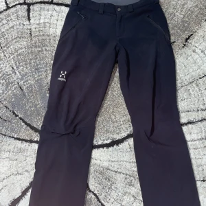  Haglöfs - Snygga svarta byxor från Haglöfs med dragkedja och knapp framtill. Perfekta för utomhusaktiviteter med en stilren design och praktiska fickor.