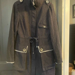 Svart kappa från ChillNorway - Säljer en elegant svart kappa från ChillNorway i storlek L. Den har långa ärmar och snygga knappar som detaljer. Kappan är perfekt för höst och vinter, med en stilren design och praktiska fickor. Den är i mycket bra skick och redo för nya äventyr!