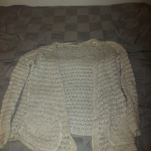 Beige stickad kofta från River Island - Mysig beige stickad kofta från River Island. Perfekt för kyliga dagar med sitt mjuka material och fina stickade mönster. Koftan har långa ärmar och en öppen design som gör den lätt att matcha med olika outfits. Ett måste för höst- och vintergarderoben! 🍂 den har ett litet större hål nära nacken, enkelt att syihop