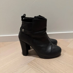 Svarta boots med klack från Samsøe Samsøe - Säljer ett par snygga svarta boots i skinn med klack och dragkedja på sidan. De har en stilren design och är perfekta för höst och vinter. Skorna är i bra skick och passar både till vardags och fest. Nypris ca 2000 kr