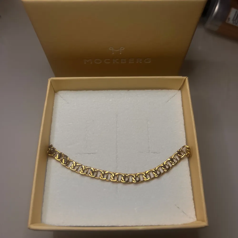 Snyggt guldarmband från Mockberg i en elegant kedjedesign. Perfekt för att ge en touch av lyx till vilken outfit som helst. Kommer i originalförpackning, vilket gör det till en fin presentidé. Passar både till vardags och festliga tillfällen. Orginalpris 699kr. . Asusteet.