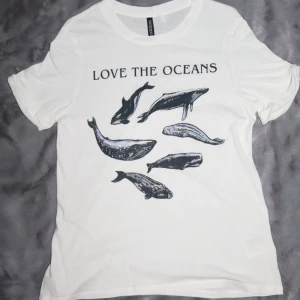 Vit t-shirt med havsmotiv - T-shirt med val-motiv. Ärmarna är uppvikta. Den har normal/lösare passform.