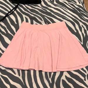 Rosa kjol från Lindex Kids - Söt rosa kjol från Lindex Kids i storlek 122. Perfekt för sommarens alla äventyr! Kjolen har en enkel och bekväm passform med resår i midjan. Den är gjord i mjukt bomullsmaterial som är skönt mot huden. Passar perfekt för både lek och festliga tillfällen. 🌸