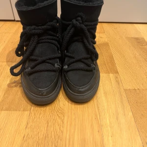 Svarta boots med snörning - Säljer ett par svarta boots från Inuikii i acceptabelt skick. De har en snygg snörning och är perfekta för vintern. Skorna är gjorda i skinn och mocka, vilket ger en cool look. Det finns lite slitage på tån och snörningen, men de är fortfarande användbara. Perfekta för kalla dagar!