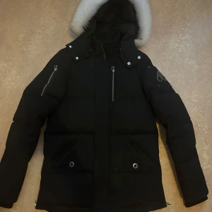Svart dunjacka från Moose Knuckles - Säljer en snygg svart dunjacka från Moose Knuckles i mycket bra skick. Jackan har en fluffig vit päls på huvan och flera praktiska fickor med dragkedjor. Perfekt för kalla vinterdagar! 🖤köpt på NK för 12 500kr 