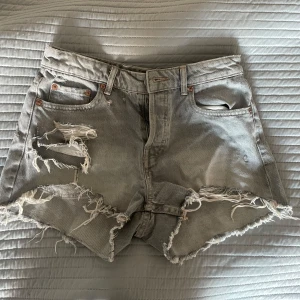 Grå jeansshorts med slitningar - Säljer ett par grå jeansshorts med coola slitningar och fransiga kanter. Från zara.