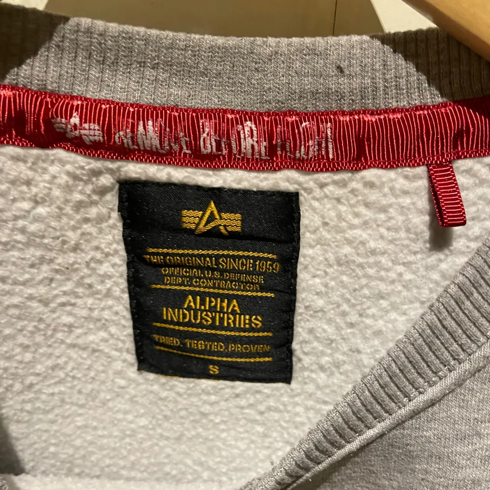 Säljer en grå sweatshirt från Alpha Industries i mycket bra skick. Väldigt lite använd. Den har ett tryck på framsidan med märkets logga och text. Tröjan är perfekt för både vardag och avslappnade tillfällen. Den är mjuk och bekväm med ribbade muddar vid ärmslut och nederkant. . Tröjor & Koftor.