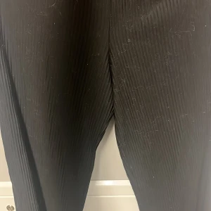 Svarta byxor från H&M - Säljer ett par svarta byxor från H&M i storlek 158/164. De är ribbade och har en elastisk midja för extra komfort. Perfekta för både vardag och festliga tillfällen. Passar bra till höst- och vintergarderoben.