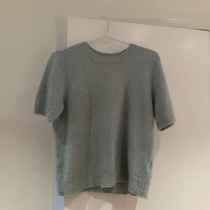 Ljusblå stickad tröja - Säljer en superfin turkos stickad tröja med korta ärmar. Perfekt för vår och sommar! Den har en rund halsringning och ribbade kanter som ger en snygg finish. Passar både till jeans och kjol för en avslappnad look.