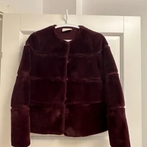 Vinröd pälsjacka från Neo Noir - Säljer en superfin vinröd faux pälsjacka från Neo Noir❤️Den är i mycket bra skick och har en mysig, lyxig känsla. Jackan har långa ärmar och knappar framtill. Perfekt för höst och vinter när du vill vara både varm och stilren. Passar perfekt till både vardag och fest! Använd en gång!