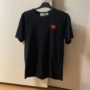 Cdg t - shirt - Säljer min svarta med rött hjärta  Comme des Garçons t - shirt då den helt enkelt inte kommer till användning. Storleken är L skulle säga att den sitter som en m/s. Bara att höra av sig som du har några övriga frågor.