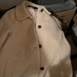 Beige teddyjacka - Mysig beige teddyjacka med stora knappar framtill. Perfekt för kyliga höst- och vinterdagar. Jackan har en klassisk krage och är i mycket bra skick. Den är både stilren och varm, vilket gör den till ett måste i garderoben!