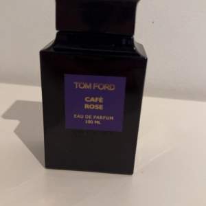 Säljer en lyxig flaska Café Rose Eau de Parfum från Tom Ford. Flaskan är elegant och svart med en lila etikett. Innehåller 100 ml av denna exklusiva doft som kombinerar ros och kaffe för en unik och sofistikerad upplevelse. Perfekt för speciella tillfällen eller som en fin present. OANVÄND