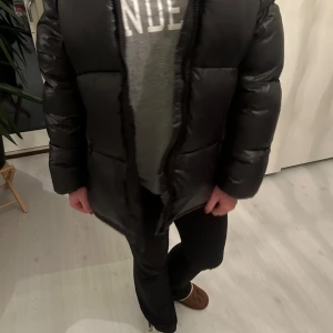 Svart pufferjacka med huva - Säljer en svart pufferjacka i mycket bra skick. Den är perfekt för kalla dagar med sin tjocka vaddering och har en praktisk huva. Jackan har en dragkedja framtill och långa ärmar. Den är både stilren och funktionell, perfekt för vinter och höst. Jag är 160cm passar perfekt!💓💓💓💓💓💓💓