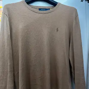 Säljer en stilren beige tröja från Polo Ralph Lauren i mycket bra skick. Den är långärmad och har en liten broderad logga på bröstet. Perfekt för både höst och vår, och passar till alla tillfällen. Skön och enkel att matcha med andra plagg!