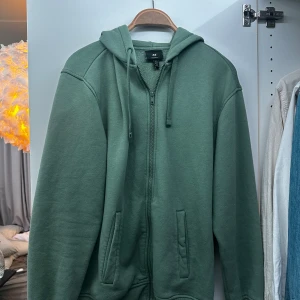 Grön hoodie från H&M - Säljer en grön hoodie från H&M i storlek S. Den har en dragkedja framtill och en avslappnad passform. Perfekt för kyliga dagar eller mysiga hemmakvällar. 🧥