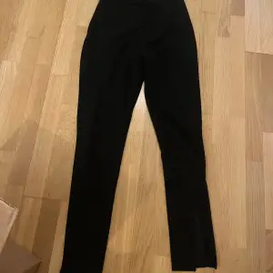 Ett par svarta kostymbyxor som är bootcut med slits