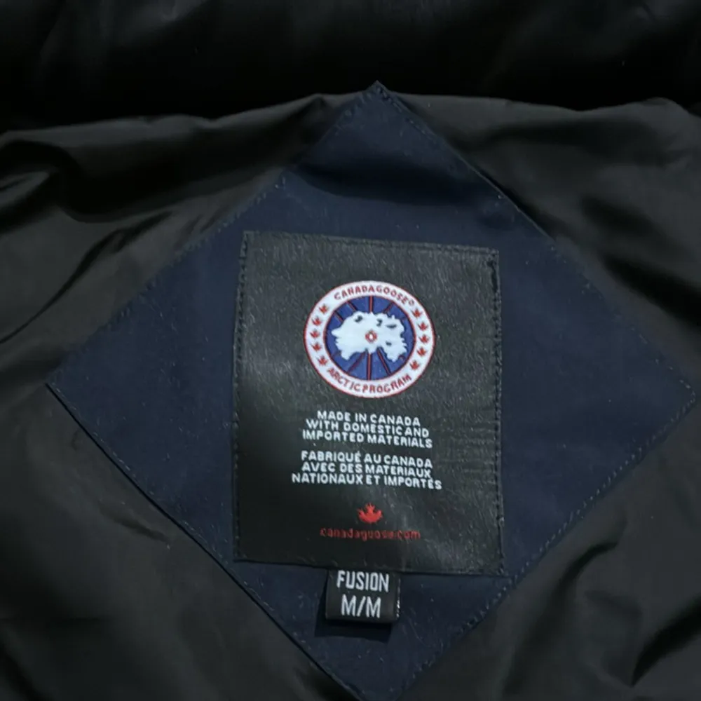 Säljer en snygg och varm svart dunväst från Canada Goose. Västen har en quiltad design med knappar framtill och en hög krage för extra värme. Perfekt för kyliga höst- och vinterdagar. Den är i storlek M och i mycket bra skick.. Jackor.