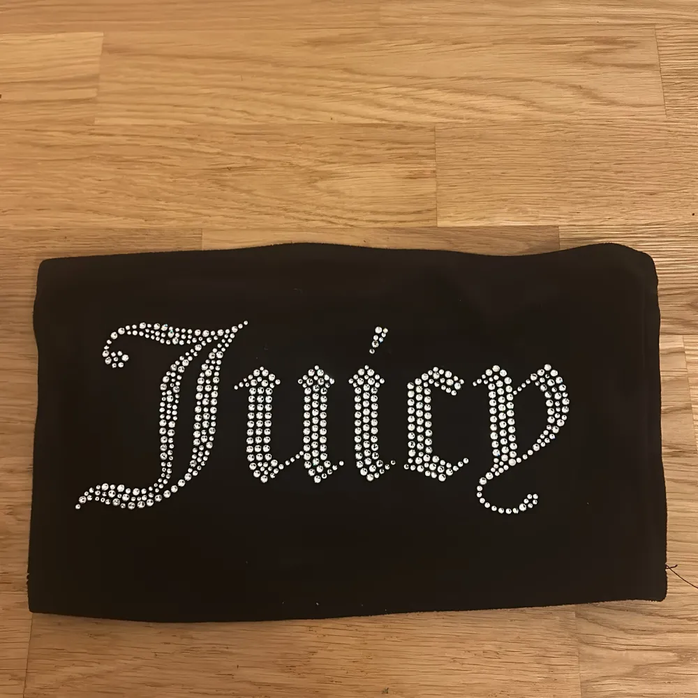 Säljer en snygg svart tubtopp från Juicy Couture. Den har ett glittrigt 'Juicy' tryck på framsidan! Perfekt för en festlig kväll eller när du vill känna dig extra glam. Toppen är i storlek XS och sitter normalt skulle också passa S! Enbart använt 3 gånger, nypris: 999.. Toppar.