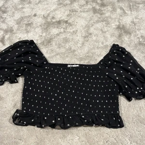 Svart topp - Svart topp med vita prickar i väldigt bra skick, knappt använd. Från NA-KD storlek 36