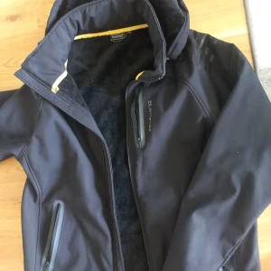 Svart jacka från Blåkläder - Säljer en svart jacka från Blåkläder. Den har en mysig fleecefoder på insidan och en praktisk dragkedja framtill. Jackan har också två fickor med dragkedjor. Perfekt för kyliga dagar!