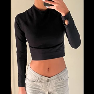 Svart croppad topp - Säljer en svart croppad topp med långärmad design. Toppen har en tight passform och är perfekt till gymmet. Materialet är mjukt och stretchigt, vilket gör den bekväm att bära hela dagen.