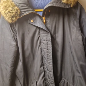 Svart parkajacka med fuskpäls från Filippa K - Säljer en snygg svart parkajacka från Filippa K i storlek medium. Jackan har en mysig fuskpäls runt huvan och en praktisk dragkedja framtill. Perfekt för kalla vinterdagar! 🖤