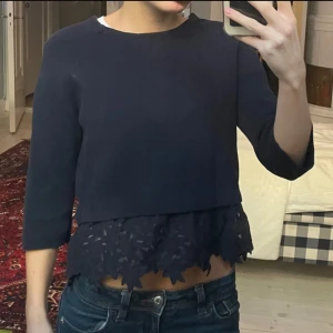 Mörkblå tröja med spetsdetalj - Säljer en mörkblå tröja med trekvartsärm och vacker spetsdetalj vid nederkanten. Perfekt för en stilren look. Passar bra till jeans eller kjol.