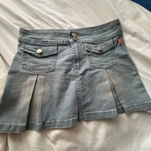 Jeanskjol med fickor - Snygg jeanskjol i ljusblå denim med två framfickor och knappar. Kjolen har en kort längd och en klassisk jeanslook. Perfekt för en avslappnad stil. Passar olika storlekar