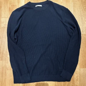 Mörkblå tröja från Zara - Säljer en stilren mörkblå tröja från Zara. Tröjan har en rund halsringning och är tillverkad i ett ribbat material. En tröja som är använda ett fåtal gånger